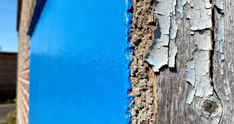 Painted wall contrasting with peeling paint in winter.